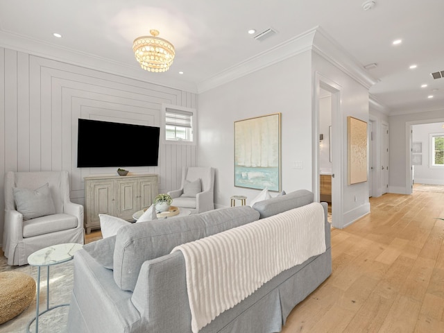 living room featuring crown molding, a healthy amount of sunlight, and light hardwood / wood-style flooring