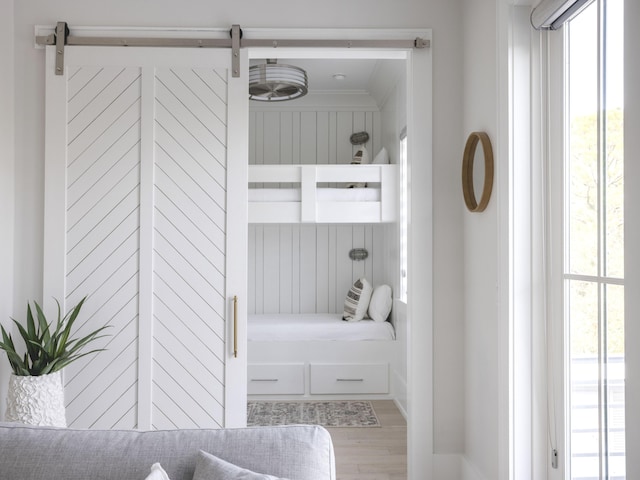 unfurnished bedroom featuring a barn door and hardwood / wood-style floors