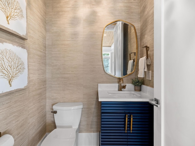 bathroom featuring vanity, toilet, and tile walls