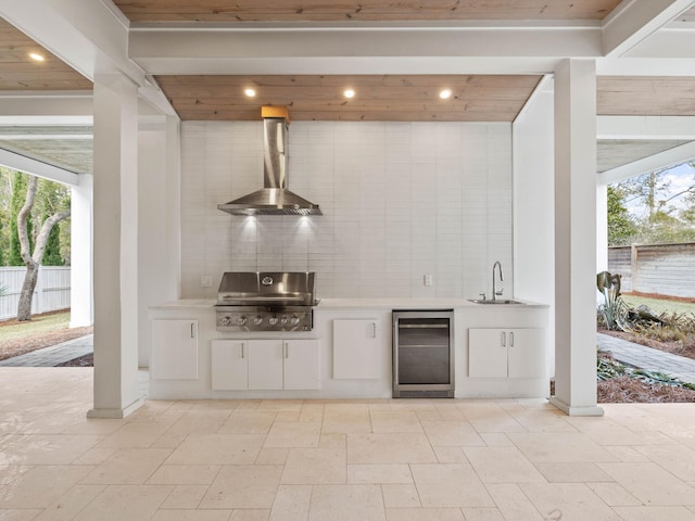 bar featuring wine cooler, wall chimney exhaust hood, sink, plenty of natural light, and white cabinets