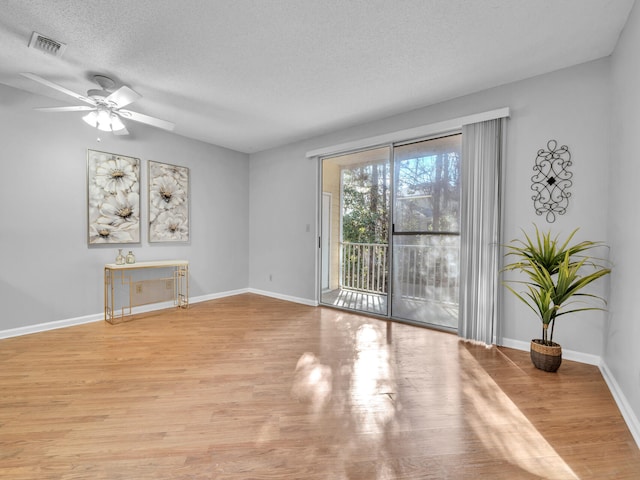 unfurnished room with baseboards, visible vents, ceiling fan, wood finished floors, and a textured ceiling