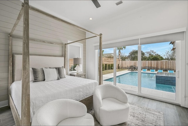 bedroom with hardwood / wood-style flooring, access to outside, ceiling fan, and wood walls