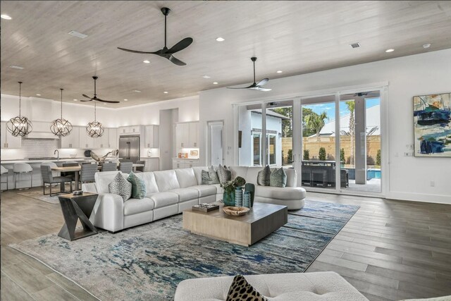 living room featuring wood-type flooring, ceiling fan with notable chandelier, and wooden ceiling