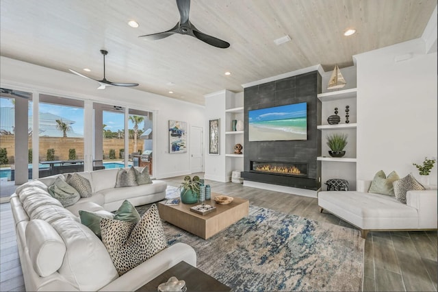 living room featuring wood ceiling, built in features, ceiling fan, wood-type flooring, and a large fireplace