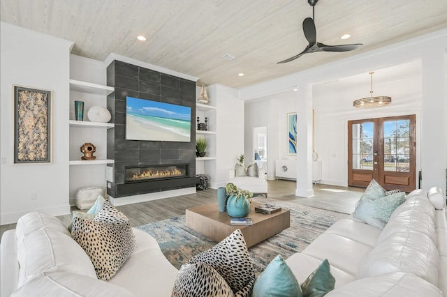 living room featuring hardwood / wood-style floors, a fireplace, built in shelves, wooden ceiling, and french doors