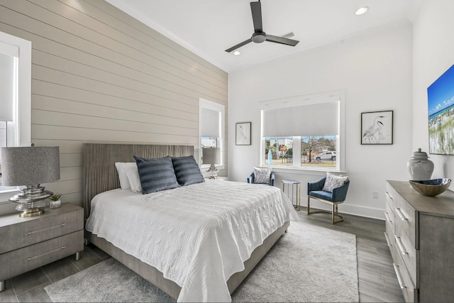 bedroom with hardwood / wood-style flooring, ceiling fan, and wooden walls