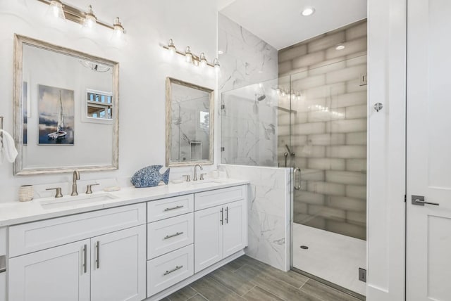 bathroom featuring a shower with door and vanity