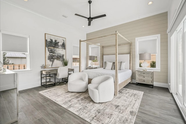 bedroom with hardwood / wood-style floors, ceiling fan, and wood walls