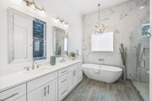 bathroom featuring vanity, hardwood / wood-style floors, shower with separate bathtub, and an inviting chandelier