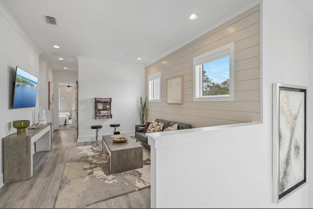 living room featuring crown molding, light hardwood / wood-style flooring, a barn door, and wood walls