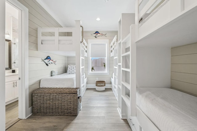 bedroom featuring light hardwood / wood-style flooring and wood walls