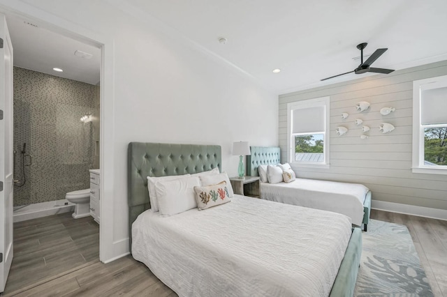 bedroom featuring multiple windows, hardwood / wood-style floors, ceiling fan, and ensuite bathroom