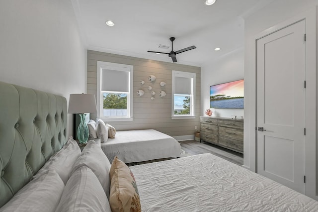 bedroom featuring ceiling fan, wooden walls, and light wood-type flooring