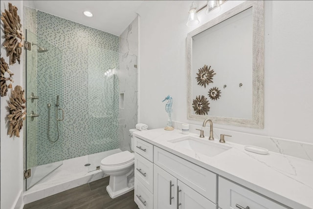 bathroom featuring vanity, toilet, a shower with door, and wood-type flooring