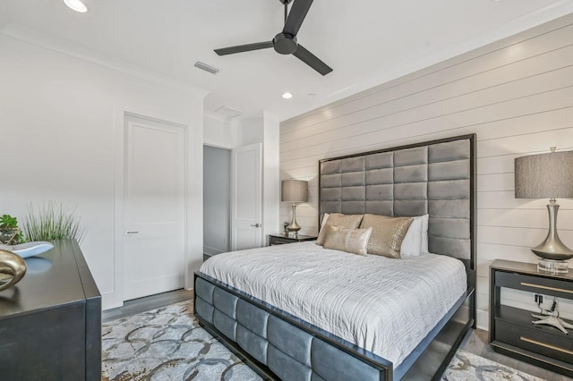 bedroom featuring wood-type flooring, wooden walls, and ceiling fan