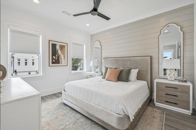 bedroom featuring hardwood / wood-style flooring, ceiling fan, and wood walls