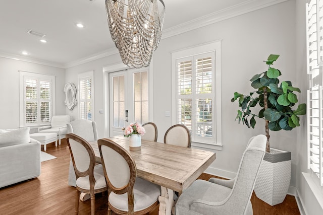 dining area featuring hardwood / wood-style flooring, crown molding, a notable chandelier, and french doors