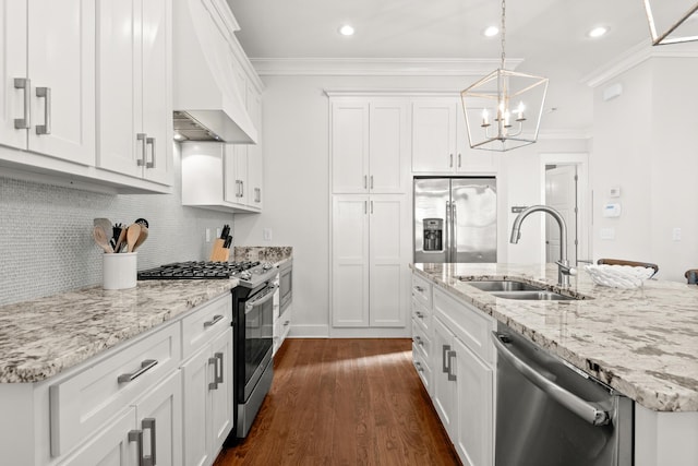 kitchen with premium range hood, sink, white cabinetry, decorative light fixtures, and appliances with stainless steel finishes