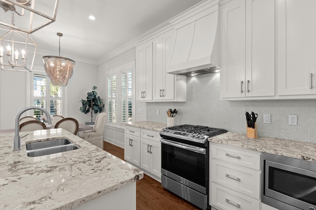 kitchen with premium range hood, sink, white cabinetry, hanging light fixtures, and stainless steel appliances