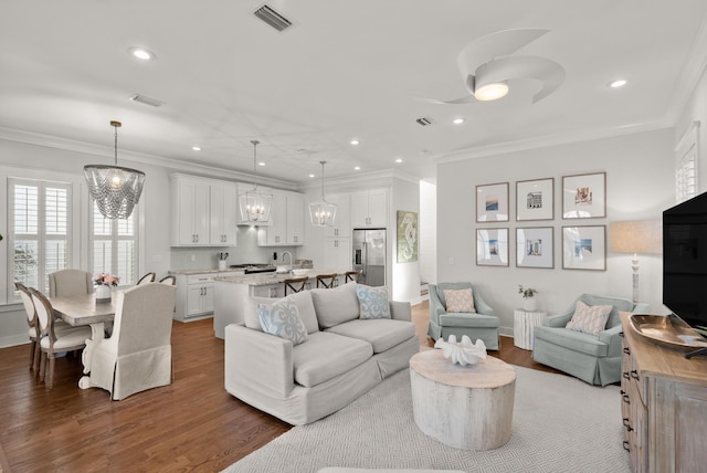 living room featuring an inviting chandelier, ornamental molding, and dark hardwood / wood-style flooring