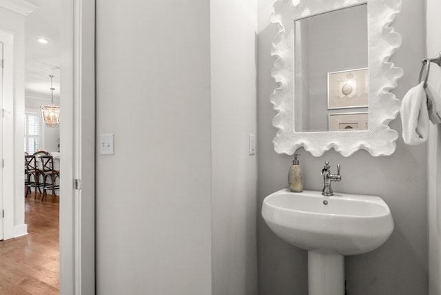 bathroom featuring hardwood / wood-style flooring, crown molding, sink, and a chandelier