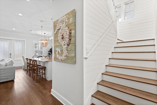 stairs featuring ornamental molding, wood-type flooring, an inviting chandelier, and french doors