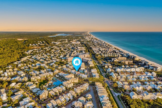 aerial view at dusk featuring a water view and a view of the beach