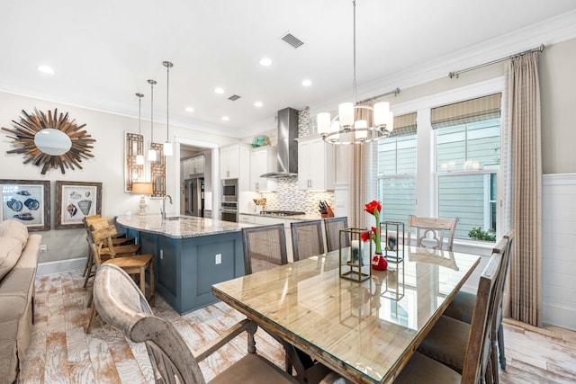 dining area featuring an inviting chandelier, ornamental molding, and sink