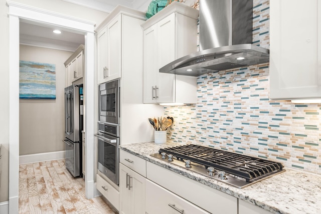 kitchen with white cabinetry, wall chimney exhaust hood, stainless steel appliances, and tasteful backsplash