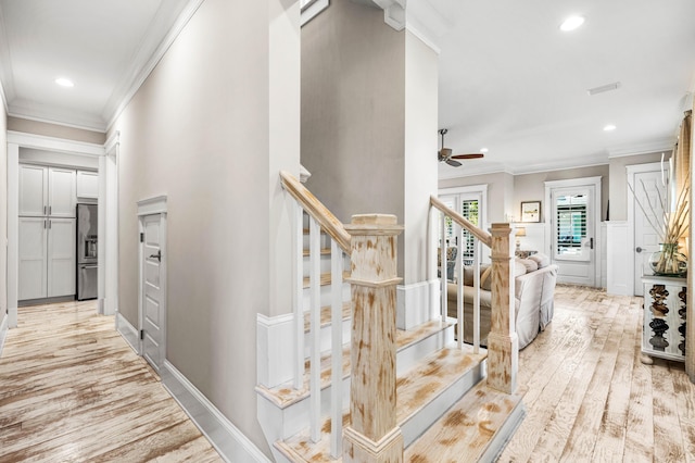 stairs with hardwood / wood-style flooring, ornamental molding, and ceiling fan