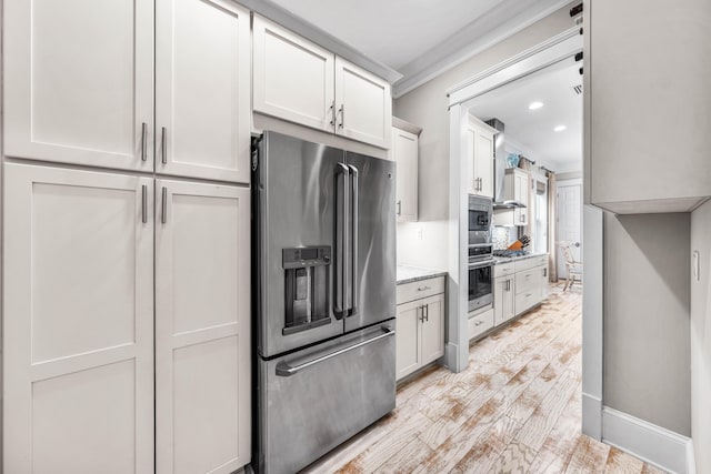 kitchen featuring crown molding, appliances with stainless steel finishes, white cabinetry, light stone counters, and light hardwood / wood-style floors