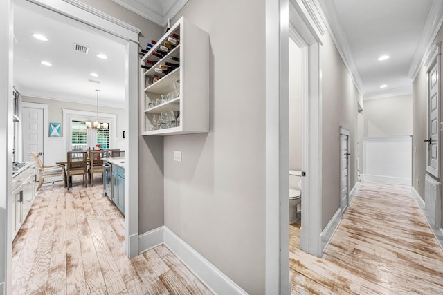 corridor featuring ornamental molding, a chandelier, and light wood-type flooring