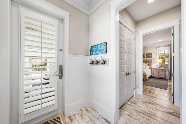 doorway featuring crown molding and light hardwood / wood-style floors