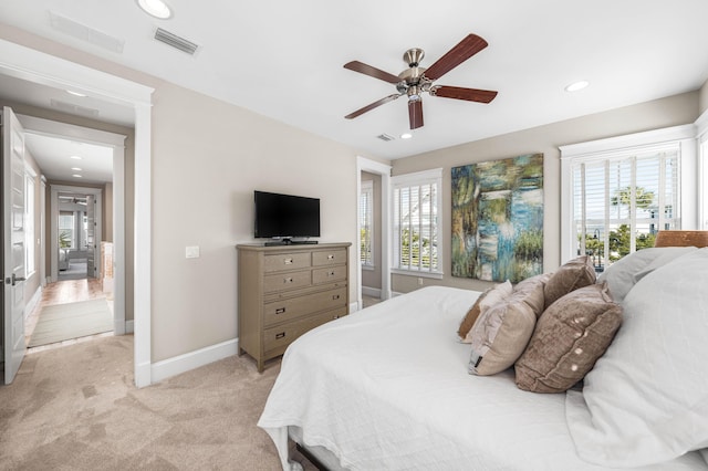 bedroom with multiple windows, light colored carpet, and ceiling fan