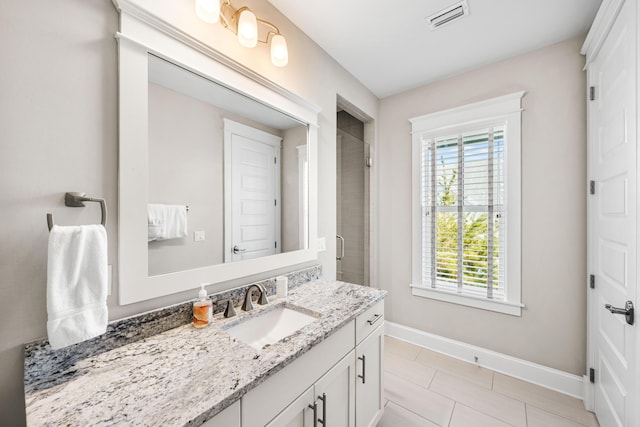 bathroom with a shower with door, vanity, and tile patterned floors