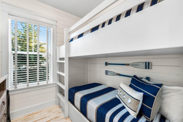 bedroom with wooden walls and light wood-type flooring