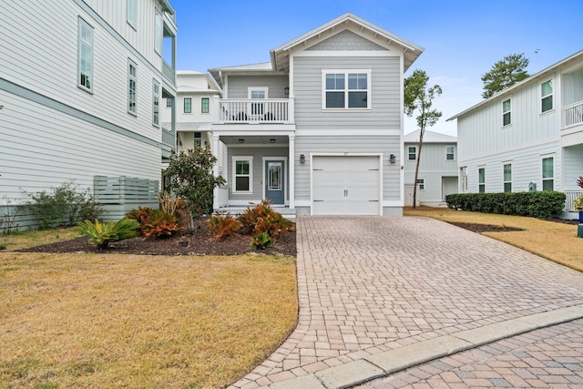 view of front facade featuring a front lawn, decorative driveway, an attached garage, and a balcony