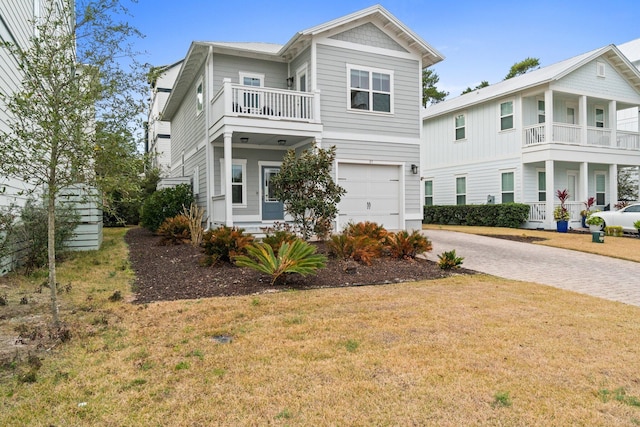 view of front facade with a garage, a front lawn, decorative driveway, and a balcony