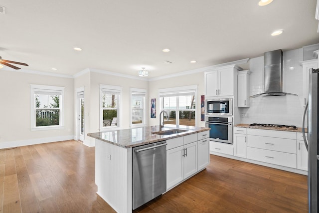 kitchen featuring wall chimney exhaust hood, a sink, light stone countertops, stainless steel appliances, and backsplash