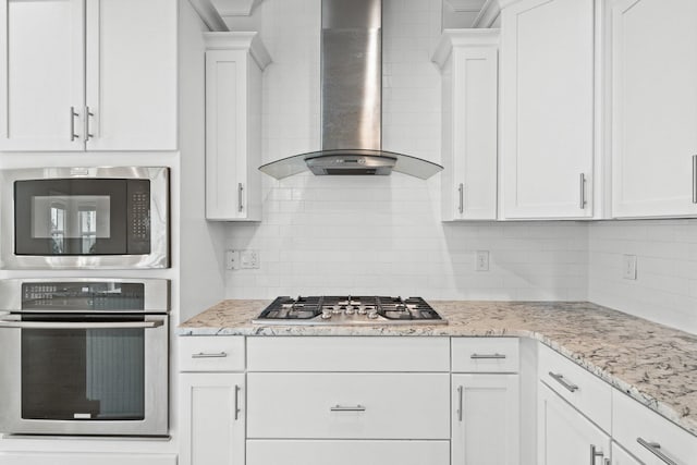 kitchen with wall chimney exhaust hood, white cabinetry, and stainless steel appliances