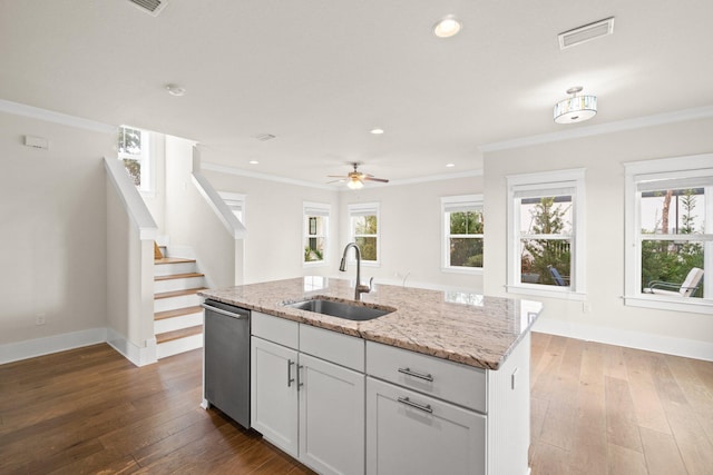 kitchen featuring visible vents, hardwood / wood-style flooring, a sink, light stone countertops, and stainless steel dishwasher