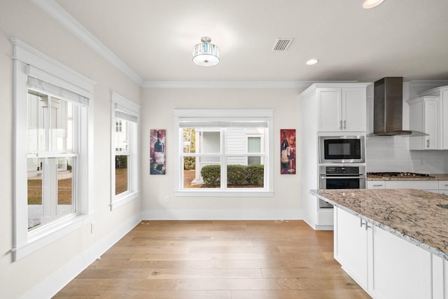 kitchen with light wood finished floors, tasteful backsplash, appliances with stainless steel finishes, ornamental molding, and wall chimney range hood