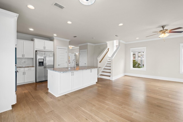 kitchen featuring light wood-style flooring, visible vents, stainless steel refrigerator with ice dispenser, and decorative backsplash