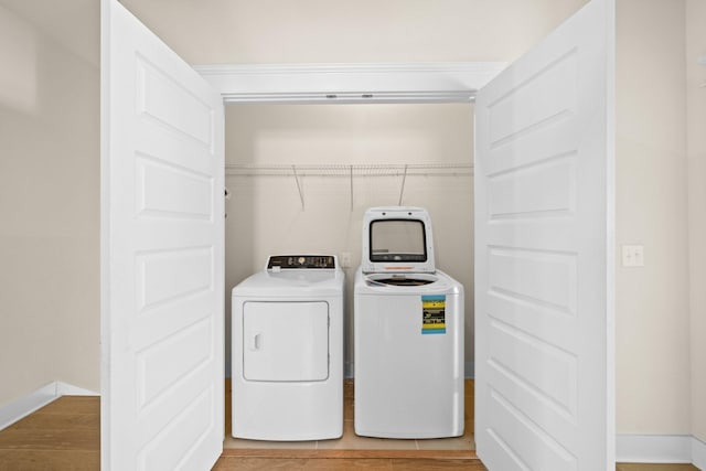 washroom featuring laundry area, washer and clothes dryer, light wood-type flooring, and baseboards