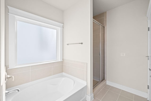 bathroom with a garden tub, tile patterned flooring, a shower stall, and baseboards