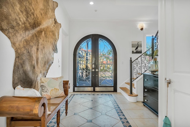 entrance foyer with light tile patterned floors, crown molding, and french doors