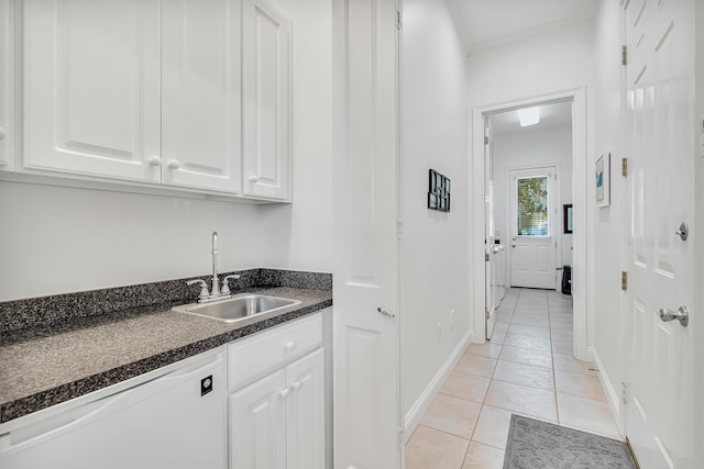 kitchen with dishwasher, sink, dark stone countertops, white cabinets, and light tile patterned floors