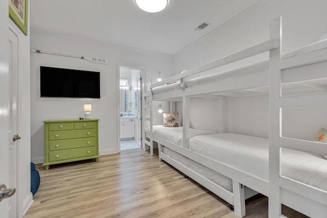 bedroom with connected bathroom, ornamental molding, and light wood-type flooring