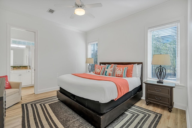 bedroom featuring ensuite bath, ornamental molding, ceiling fan, and light wood-type flooring