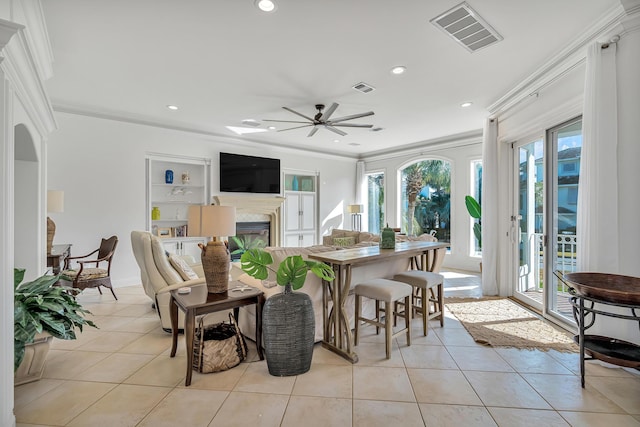 living room with built in shelves, ceiling fan, ornamental molding, and light tile patterned floors